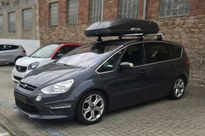 Eine Dachbox Modell Trivor von HAPRO mit THULE-Wingbar-Dachträgern auf einem Ford S-Max